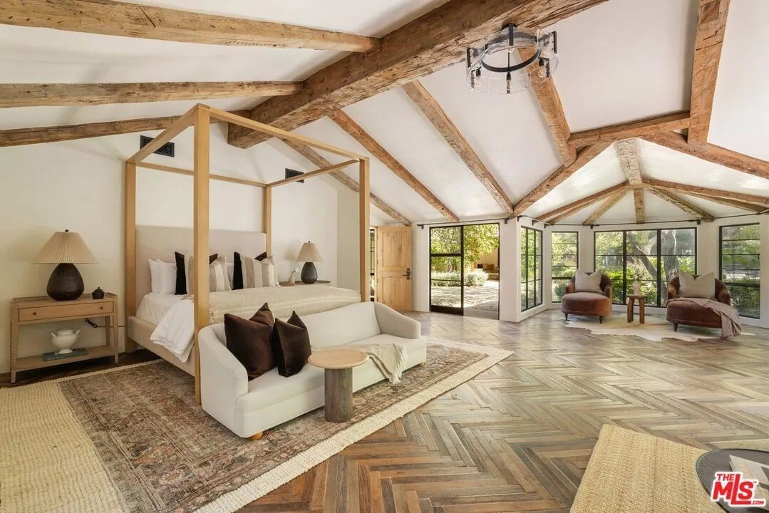 The main house's spacious primary suite features chevron wood flooring, a sunny sitting area and a large, boutique style closet.