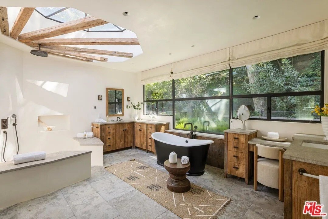 The unique primary bath has a rustic yet modern vibe, and is illuminated by a dramatic skylight.
