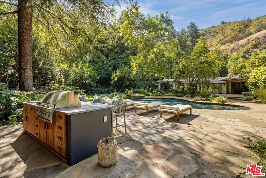 In back, there's a solar-heated pool and spa, plus an outdoor kitchen with a with a grill and pizza oven, and multiple dining areas.