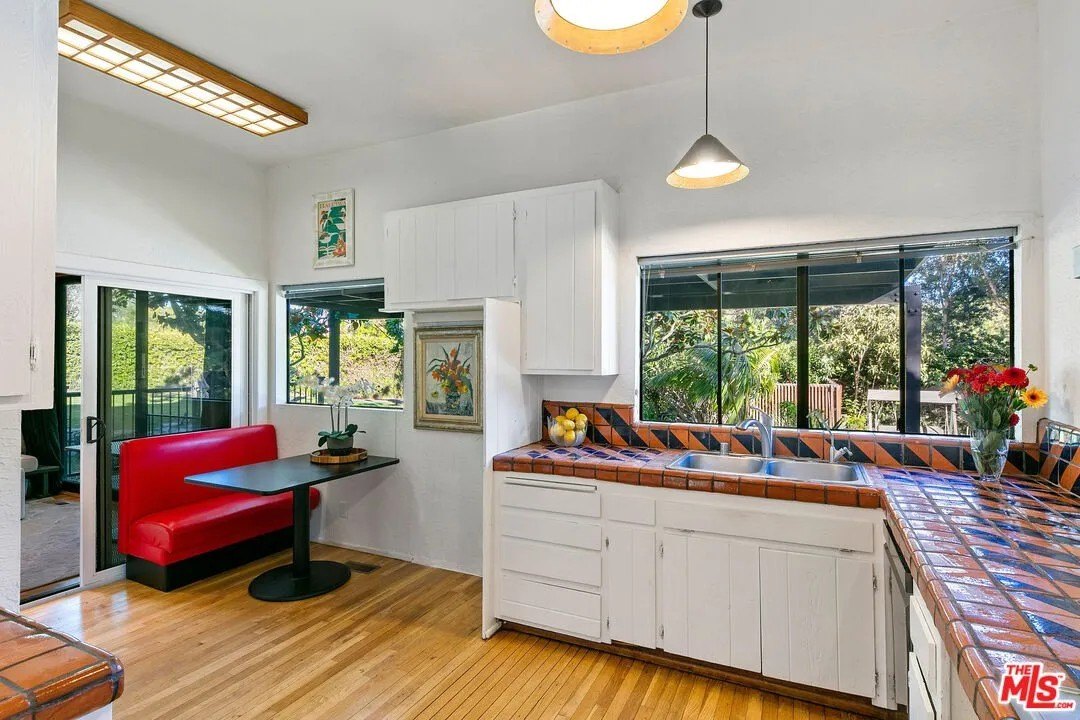 The kitchen features handcrafted tile work, white custom cabinetry, and a breakfast nook with a built-in banquette.